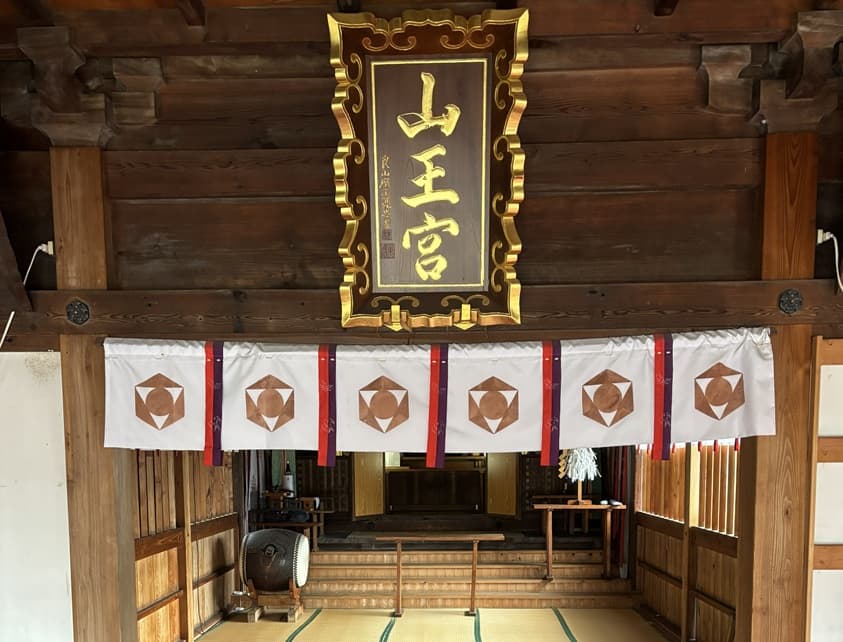 山王宮の扁額と神紋の幕が飾られた拝殿内部